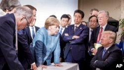 La chancelière allemande Angela Merkel, au centre, s'entretient avec le président américain Donald Trump, assis à droite, lors du Sommet des dirigeants du G7 à La Malbaie, Québec, Canada le 9 juin 2018 (Jesco Denzel/German Federal Government via AP).