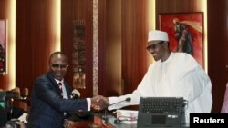 Ibe Kachikwu, Directeur Général du Groupe de la Compagnie Nationale du Petrole du Nigeria (NNPC) et nouveau ministre nigérian du pétrole, serre la main du président Muhammadu Buhari (D) lors d'une cérémonie d'investiture à Abuja, au Nigeria 11 novembre, 2015.