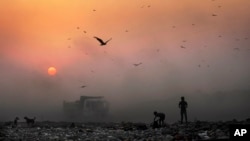 Asap tebal terlihat di angkasa sementara anak-anak pemulung mencari barang yang bisa didaur ulang di tempat pembuangan sampah di New Delhi, India. (Foto: Dok)