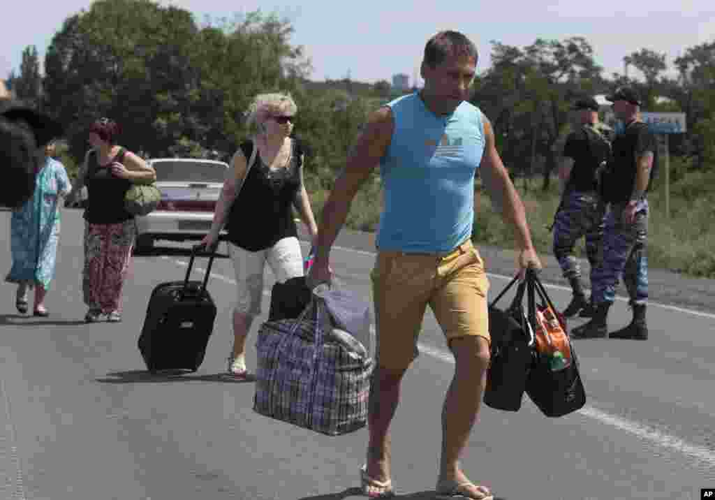 Self-proclaimed Donetsk People's Republic policemen watch people fleeing Shakhtarsk, Donetsk region, eastern Ukraine, July 28, 2014.