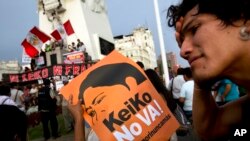 Seorang pria memegang spanduk dalam aksi unjuk rasa menentang pencalonan kandidat capres Keiko Fujimori, dan ayahnya, mantan Presiden Alberto Fujimori,di pusat kota Lima, Peru (5/4).