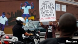 FILE - A demonstrator blocks the path of a Los Angeles Police Department officer during a rally against the decision in the Michael Brown case and the LAPD's fatal shooting in August of Ezell Ford, in Los Angeles, Dec. 1, 2014.