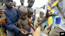 A man distributes bread to children at Abidjan's St. Ambrose church, a temporary refuge for people who fled from clashes between forces loyal to Laurent Gbagbo and Alassane Ouattara (File)