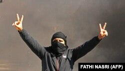 Un Tunisien brandit le V comme signe de victoire alors que des jeunes brûlent des pneus et bloquent des routes dans la ville de Tataouine, au sud du pays, le 12 février 2021.