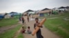 FILE - A Rohingya boy walks with a mat as children play in the background at Dar Paing camp for Muslim refugees in north of Sittwe, western Rakhine State, Myanmar. 
