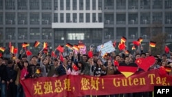 資料照：中國安徽省合肥市的德國大學學生們手持中德橫幅和中德國旗等待德國時任總理默克爾的訪問。 (2015年10月30日)