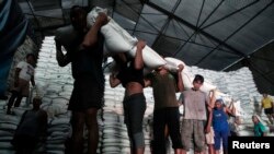 Para pekerja pabrik gula di Sidoarjo, Jawa Timur, mengangkut karung-karung berisi gula dari gudang ke truk untuk didistribusikan. (Foto: Dok)