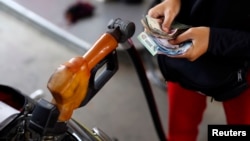 Pegawai sebuah pom bensin di Jakarta menghitung uang sambil mengisi bahan bakar bersubsidi untuk sepeda motor. 