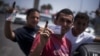 Libyan men hold their elections ID cards while celebrating election day in Tripoli, Saturday, July 7, 2012. 
