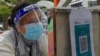 A woman wearing protective mask scans a QR code before queuing up to get tested for the coronavirus at a temporary testing center for COVID-19 in Hong Kong, Feb. 24, 2022. 