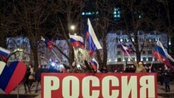 La gente ondea banderas nacionales rusas para celebrar, en el centro de Donetsk, el territorio controlado por militantes prorrusos, en el este de Ucrania, el lunes 21 de febrero de 2022 por la noche.