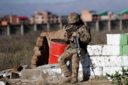 A soldier guarding the Senkata fuel plant reads from a mobile device, in El Alto, Bolivia, Nov. 22, 2019.