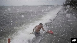 Ombak mengenai seorang warga Filipina ketika mengambil sandal karetnya di Manila Bay, Filipina, 10 Mei 2015.
