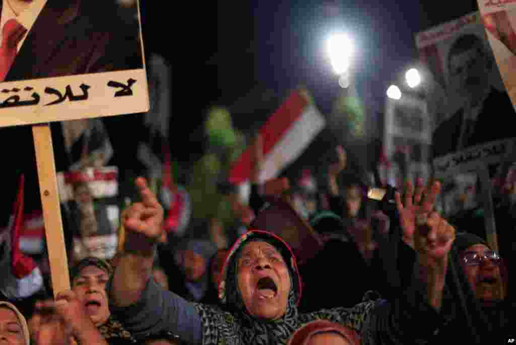 Supporters of Egypt's ousted President Mohamed Morsi chant slogans and hold posters with Arabic writing which reads "Yes for legality, No for the coup" during a protest outside Rabaah al-Adawiya mosque, Cairo, August 6, 2013.