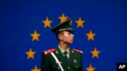 Seorang polisi paramiliter China sedang bertugas di depan bendera Uni Eropa di luar kantor delegasi Uni Eropa untuk China, di Beijing, 28 Oktober 2011. (Foto: AP)