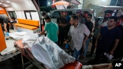 Petugas medis Palestina memindahkan jenazah korban pengeboman Israel terhadap Al Zawayda di tengah Jalur Gaza ke kamar jenazah rumah sakit Al Aqsa di Deir al Balah, Jalur Gaza, Rabu, 22 Mei 2024. (Foto: Abdel Kareem Hana/AP Photo)