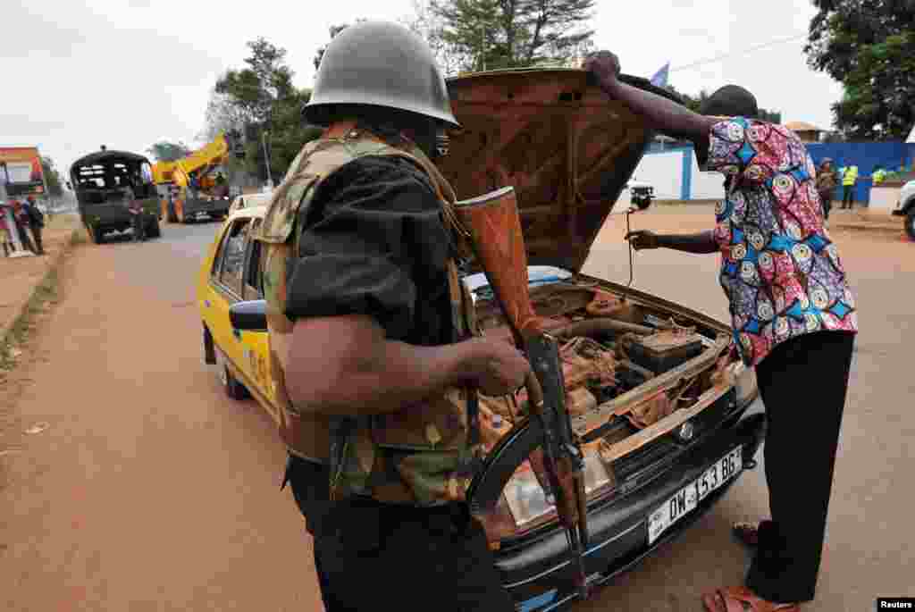 Polisi memeriksa mobil di pos keamanan distrik PK4 di Bangui (27/2). (AFP/Sia Kambou)