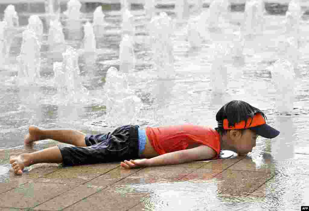 Seorang bocah Korea Selatan menelungkupkan badannya sambil mendinginkan diri di sebuah air mancur saat gelombang panas menghantam pusat kota Seoul, 12 Agustus 2013.