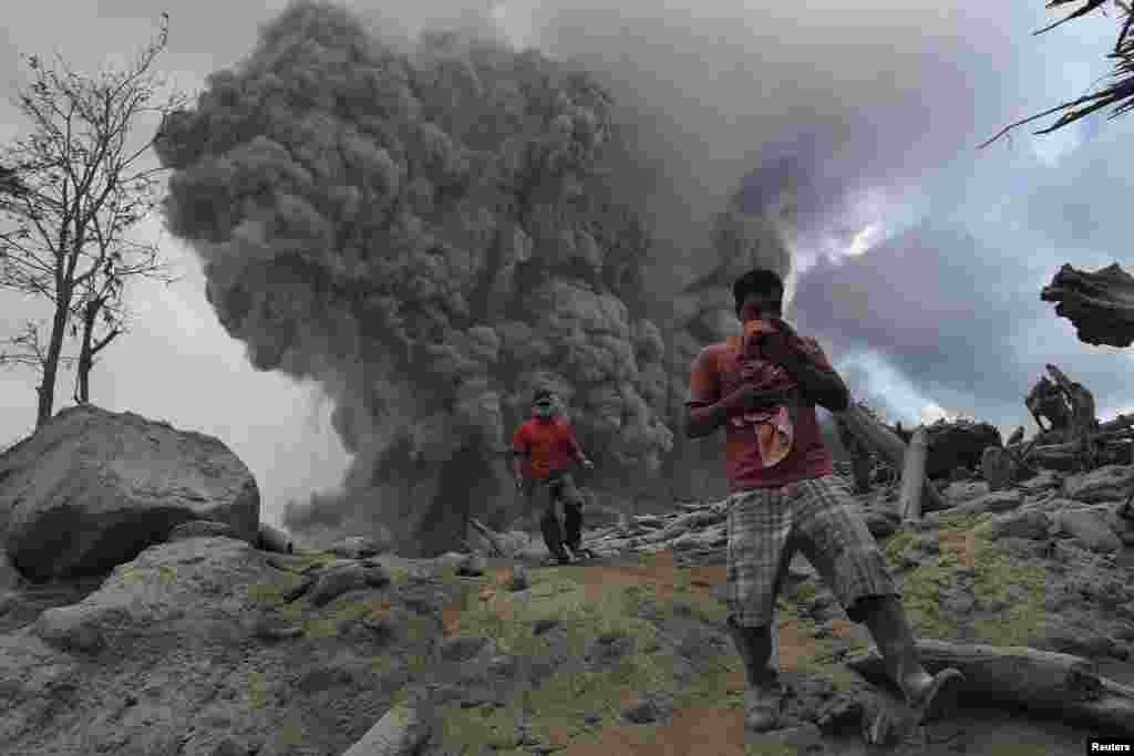Warga berusaha menghindari abu vulkanik yang dimuntahkan oleh letusan Gunung Sinabung di desa Gamber, Kabupaten Karo, Sumatra Utara, Selasa (21/1).