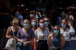 Tourists wearing face masks wait to cross a road in downtown Barcelona, Spain, July 16, 2020.