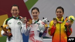 Qi Xinyi dari China (tengah), meraih medali emas wushu untuk nomor changquan putri, bersama peraih medali perak Li Yi (kiri) dari Macau dan peraih medali perunggu, Hoang Thi Phuong Giang dari Vietnam, 22 Agustus 2018.