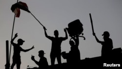 Para pengunjuk rasa Irak berdiri di tembok dalam demonstrasi anti-pemerintah dekat gedung pemerintahan di Basra, Irak, 7 September 2018.