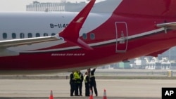 Anggota kru berbincang dekat pesawat Boeing 737 MAX 8 yang dioperasikan Shanghai Airlines di landasan Bandara Hongqiao di Shanghai, China, 12 Maret 2019. 