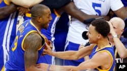 Stephen Curry (30) et Andre Iguodala (9), nouveaux champions de la NBA 2015, célèbrent leur victoire sur les Cavaliers, Cleveland, le 16 juin 2015. (AP Photo/Paul Sancya) 