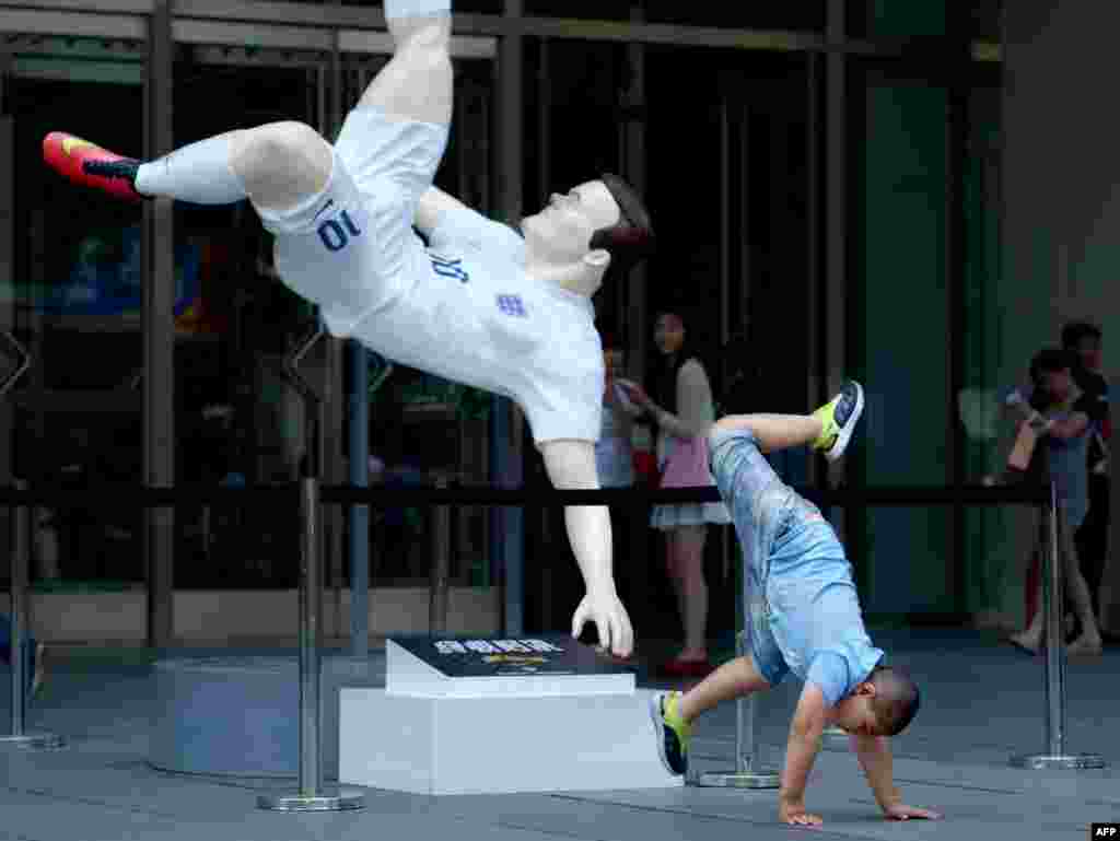Seorang anak laki-laki berpose untuk difoto di depan patung pemain sepak bola Inggris Wayne Rooney di pintu masuk sebuah mal di Beijing, China. 
