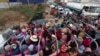Cambodian garment factory workers ride on the back of a truck as they head to their homes at the evening traffic jump of Sre Cheah village outside Phnom Penh, Cambodia, Saturday, Jan. 11, 2020. (AP Photo/Heng Sinith)