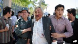 A wounded man is assisted after gunmen stormed a courthouse in Mazar-i-Sharif, north of Kabul, Afghanistan, April, 9, 2015. 