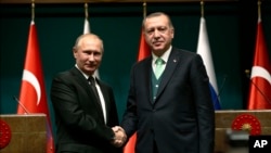 Presiden Turki Recep Tayyip Erdogan, kanan, berjabat tangan dengan Presiden Vladimir Putin, kiri, setelah konferensi pers bersama mengenai pertemuan mereka di Istana Kepresidenan di Ankara, 11 Desember 2017. 