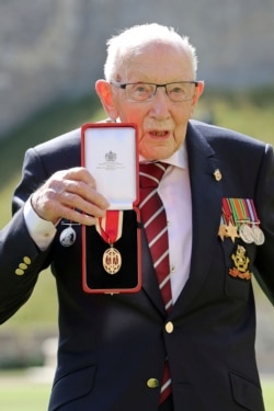 Captain Sir Thomas Moore poses for the media after receiving his knighthood from Britain's Queen Elizabeth, during a ceremony at Windsor Castle in Windsor, England, July 17, 2020.