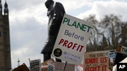 FILE - Climate change demonstrators hold banners in front of the Winston Churchill Statue during a protest near Parliament in London, April 12, 2019. 