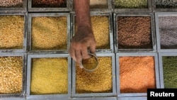 An employee collects lentils from a container inside a grocery store at a residential area in Mumbai, India. (Credit Reuters)