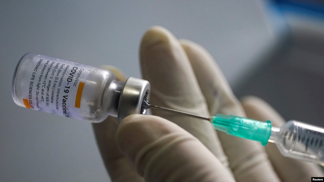 FILE PHOTO: A health worker holds a syringe and a vial of the Sinovac coronavirus disease (COVID-19) vaccine at a market in Bangkok, Thailand, March 17, 2021. REUTERS/Athit Perawongmetha/File Photo
