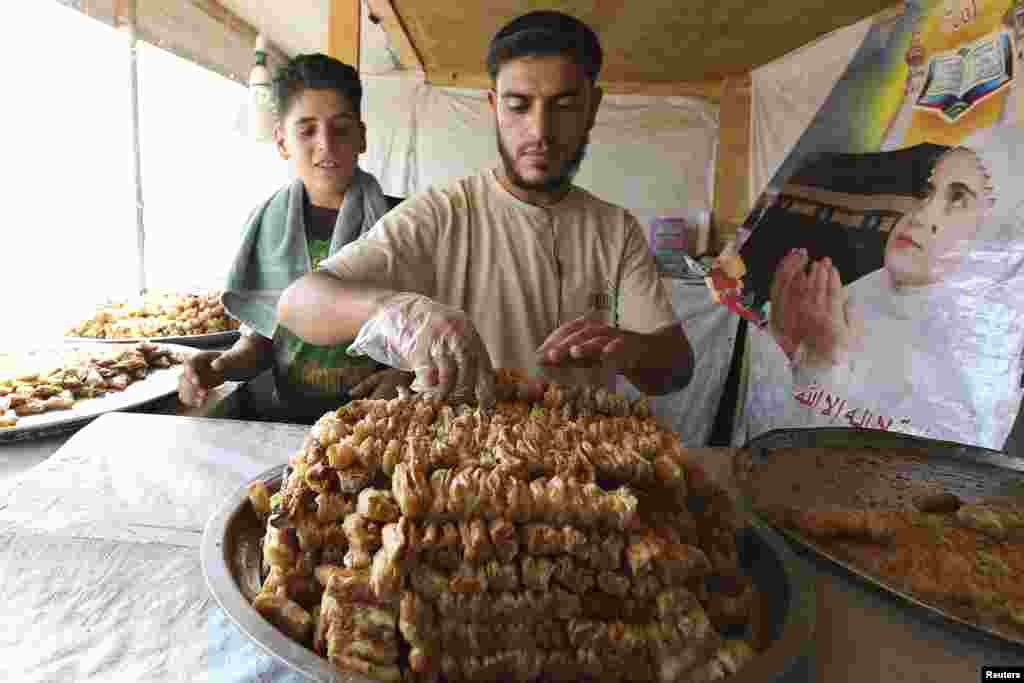 A Syrian refugee displays sweets for sale during the month of Ramadan at Al Zaatri refugee camp in the Jordanian city of Mafraq, near the border with Syria, July 30, 2013. 