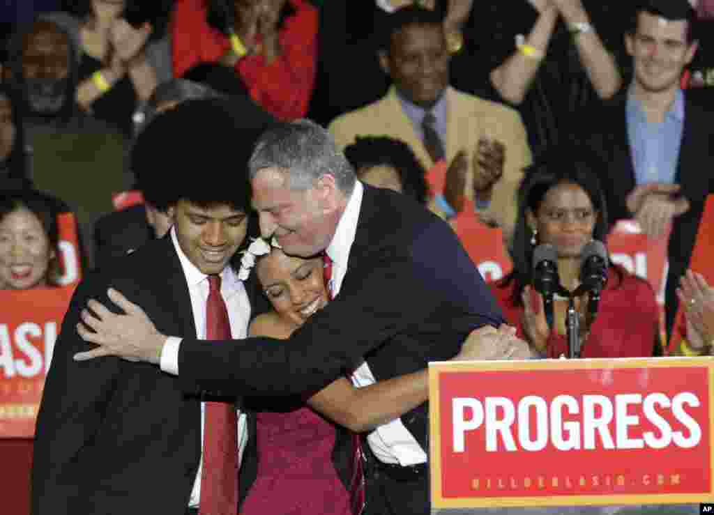 Walikota New York City Bill de Blasio dari Partai Demokrat memeluk putranya Dante (kiri) dan putrinya Chiara (tengah), setelah ia terpilih di Brooklyn, New York. De Blasio menang telak atas Joe Lhota dari Partai Republik, menggantikan miliuner Michael Bloomberg, calon independen yang telah tiga periode menjabat sebagai walikota. (AP/Kathy Willens) 