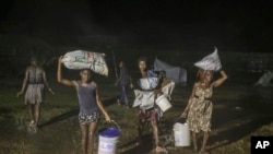 Penyintas gempa berjalan di tengah hujan tropis Grace di kamp pengungsi Les Cayes, Haiti, Senin, 16 Agustus 2021. (AP Photo/Joseph Odelyn)
