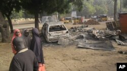 Des enfants deiscutent près du lieu d'une explosion au marché de Potiskum, Nigeria, le 12 janvier 2015.