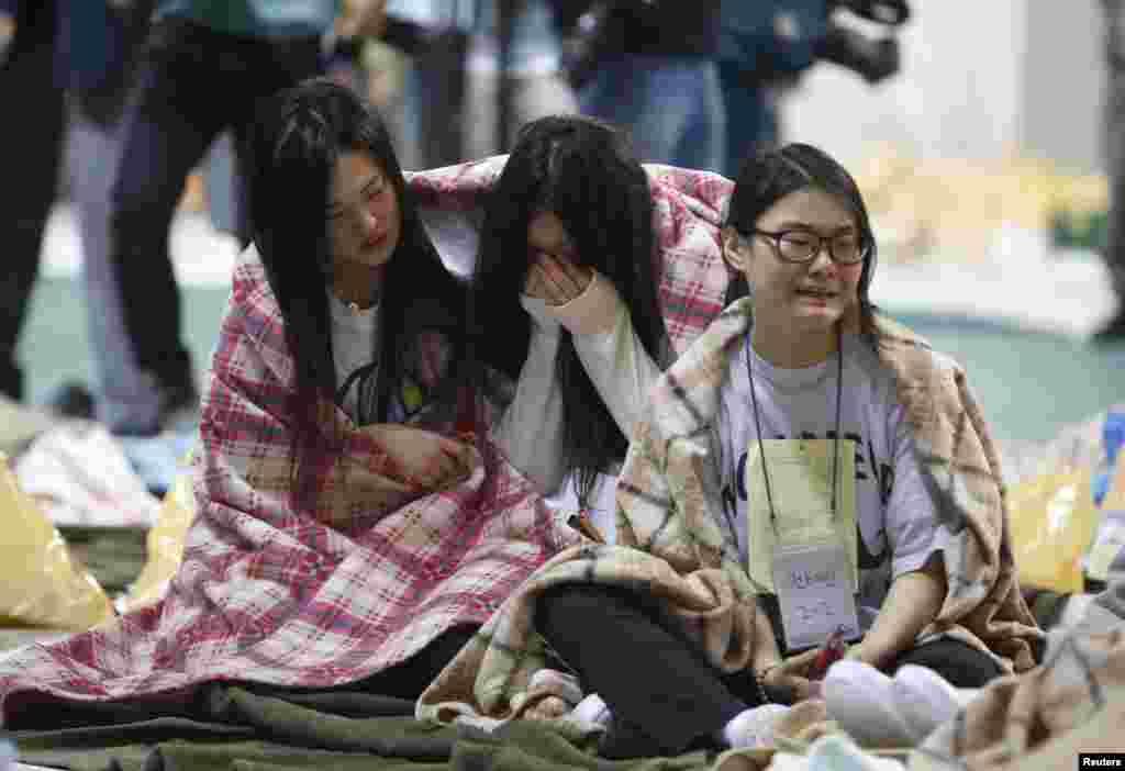 Para penumpang yang selamat menangis dalam klub kebugaran yang menjadi tempat penampungan sementara penumpang yang selamat di Jindo, Korea Selatan.
