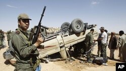 Un soldat tunisien devant un vévicule accidenté appartenant aux troupes de Mouammar Kadhafi