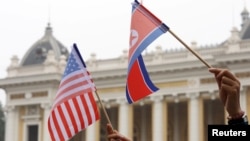 Warga memegang bendera AS dan Korea Utara saat menunggu rombongan pemimpin Korea Utara Kim Jong Un dalam pertemuan di kedua AS-Korut di Hanoi, Vietnam, 28 Februari 2019. (Foto: Kham/Reuters)