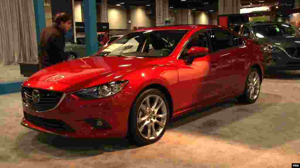 Un asistente a la feria de autos en Washington aprecia los atributos del nuevo Mazda.