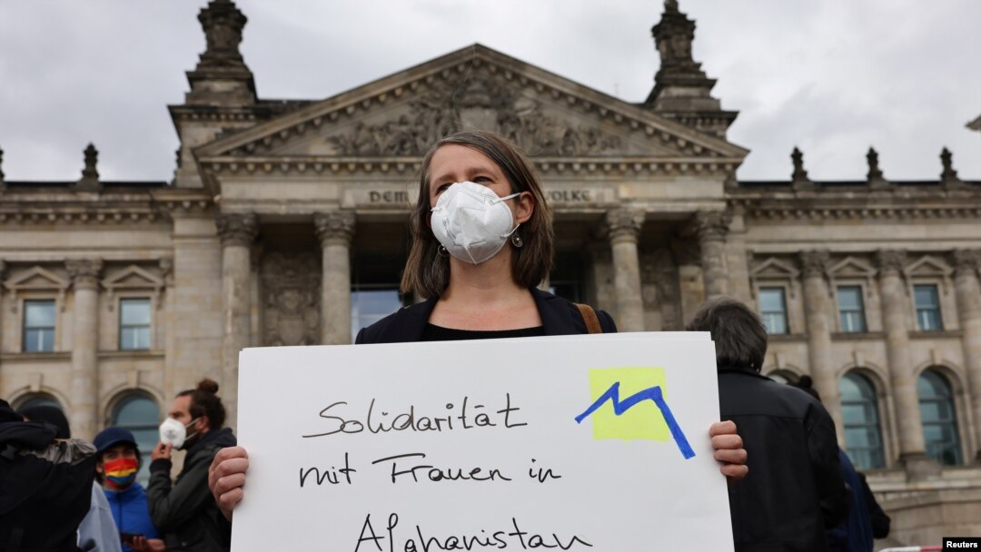 A person holds a placard reading "Solidarity with women in Afghanistan" during a protest against support for the Taliban, in front of the lower house of parliament, the Bundestag, in Berlin, Germany, Aug. 17, 2021.