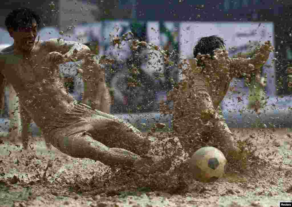 Players battle for the ball during a match at the swamp soccer China tournament in Beijing.