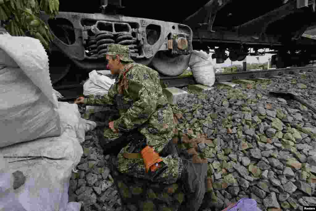 A pro-Russia rebel takes a front line position behind railway cars following early morning shelling by Ukrainian forces, south of the eastern Ukrainian city of Slovyansk, May 12, 2014.