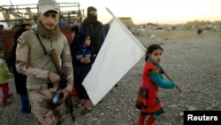 FILE - A girl who had just fled Kokjali near Mosul carries a white flag as she arrives with her family at a peshmerga checkpoint east of Mosul, Iraq, Nov. 3, 2016. 