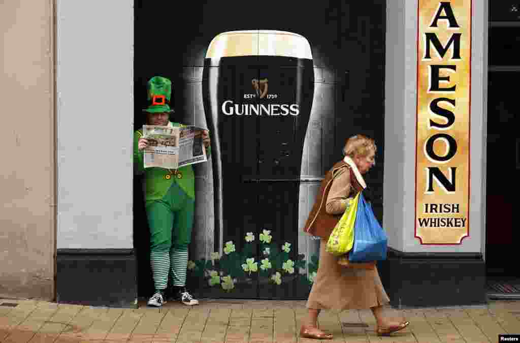 Seorang pria berpakaian Leprechaun membaca koran dalam perayaan Hari St Patrick di kota Londonderry, Irlandia Utara.