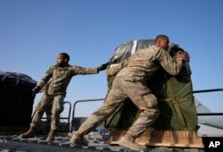 Sejumlah tentara AS memuat kontainer berisi bantuan kemanusiaan ke sebuah pesawat di Pangkalan Udara Al-Udeid, Qatar, Jumat, 29 Maret 2024. (Foto: Hussein Malla/AP Photo)